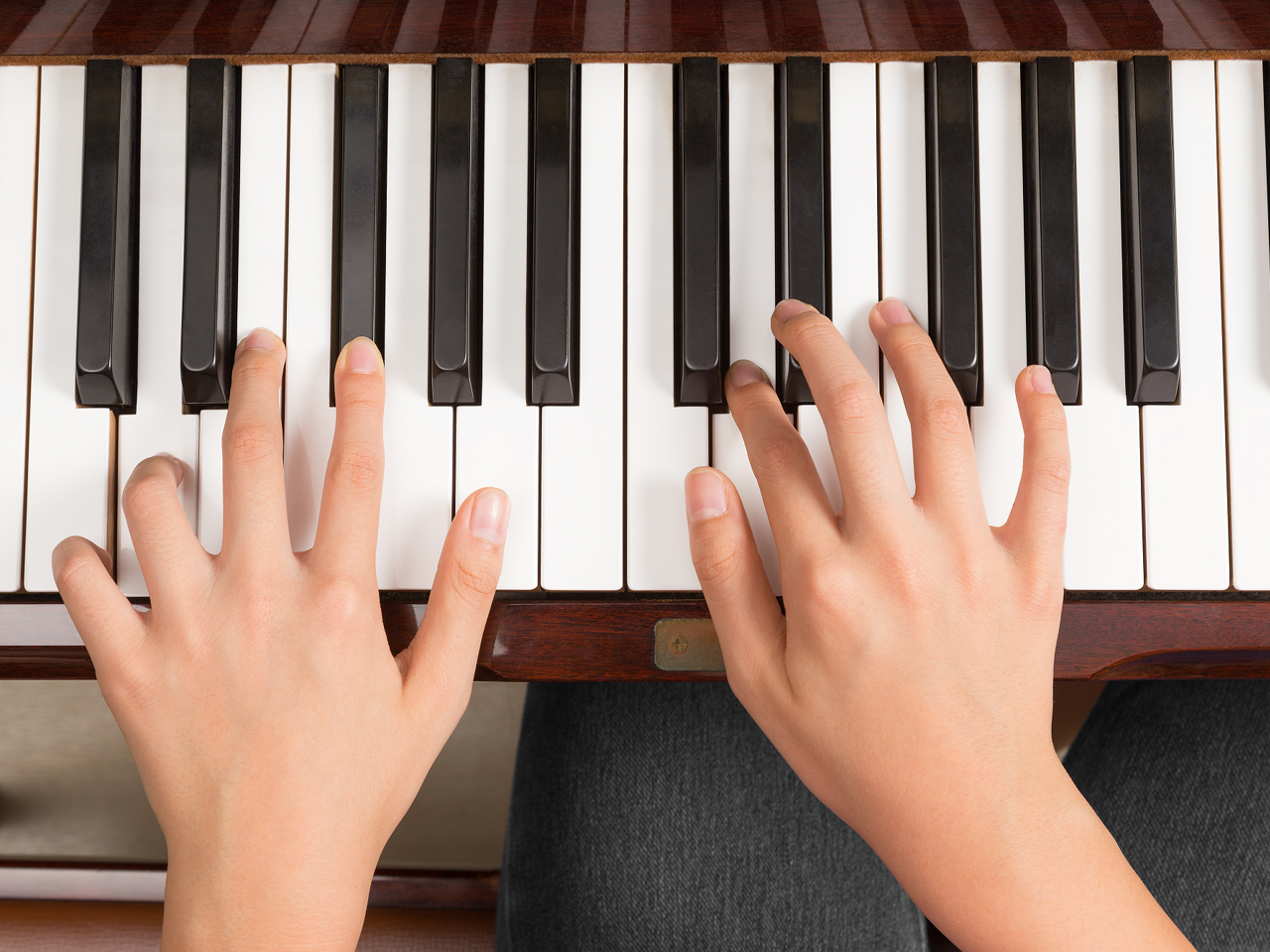 Foto af børnehænder over et klaviatur.