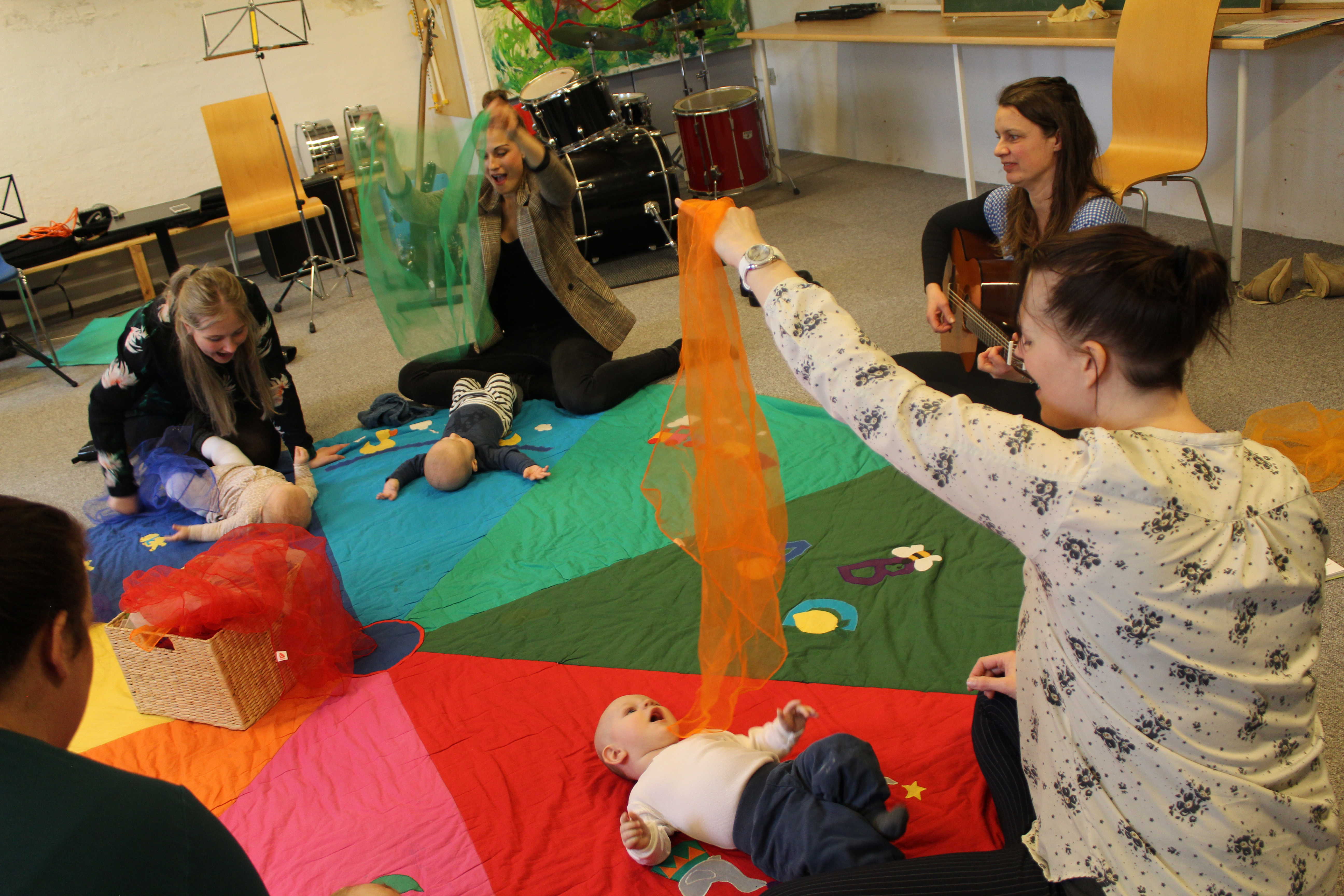 Billede af mødre med babyer og musiklærer med guitar